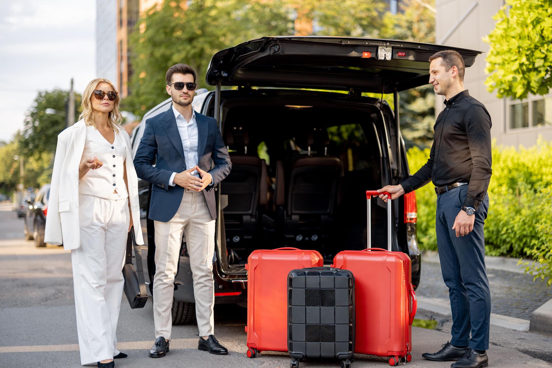 Business couple near minivan taxi with a suitcases and chauffeur